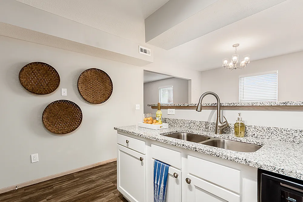 Modern kitchen with stylish granite countertops, dual sinks, and elegant lighting, featuring decorative wall accents and a cozy ambiance.
