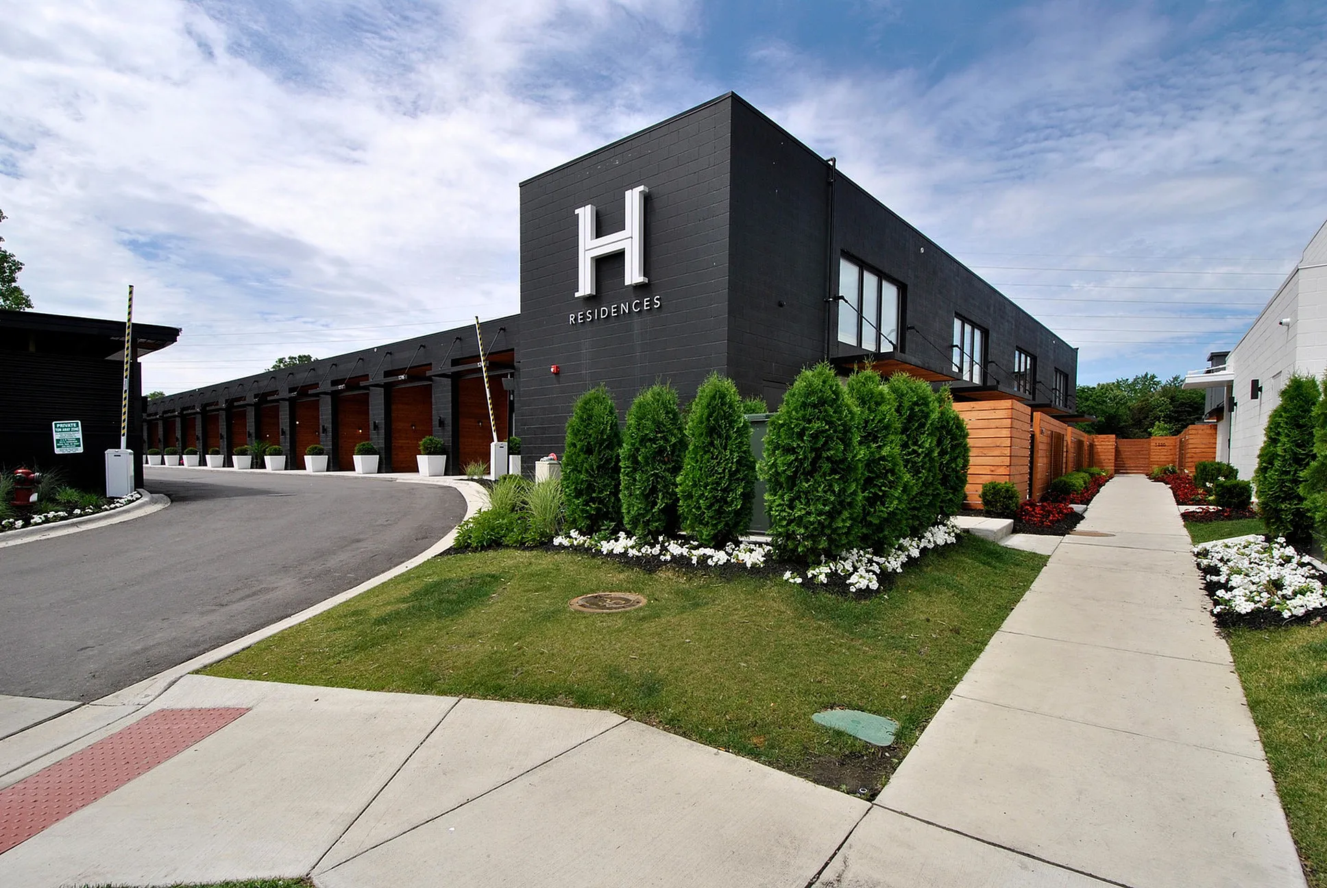 Modern apartment complex with sleek architecture, vibrant landscaping, and welcoming entrance at H Residences.
