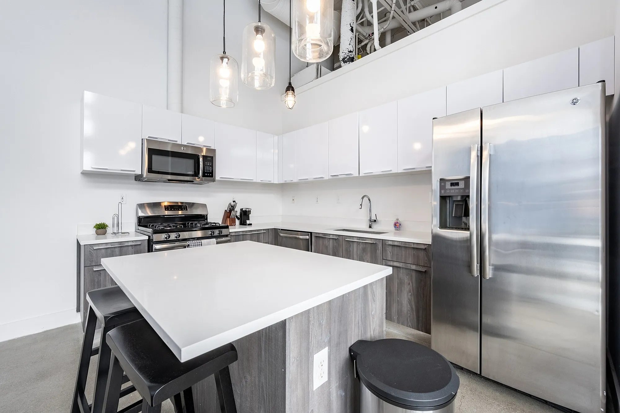 Modern kitchen with sleek stainless steel appliances, elegant pendant lighting, and a spacious island with bar seating.