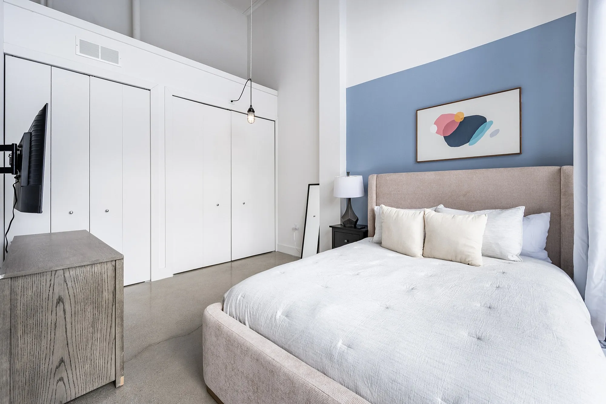 Chic and serene bedroom with modern decor, featuring a plush bed, elegant artwork, and ample closet space.
