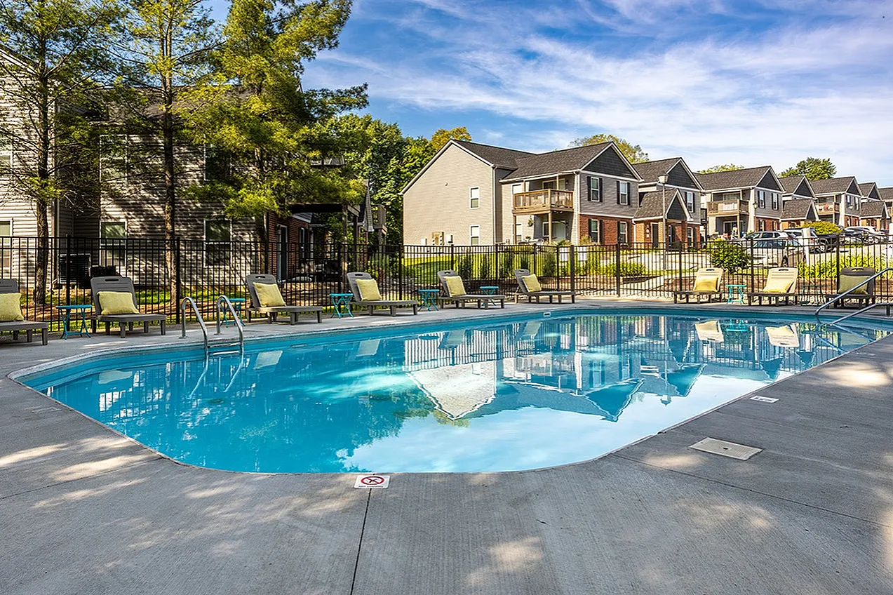 Inviting residential community with a sparkling pool, surrounded by stylish lounge chairs and lush greenery for relaxation and enjoyment.