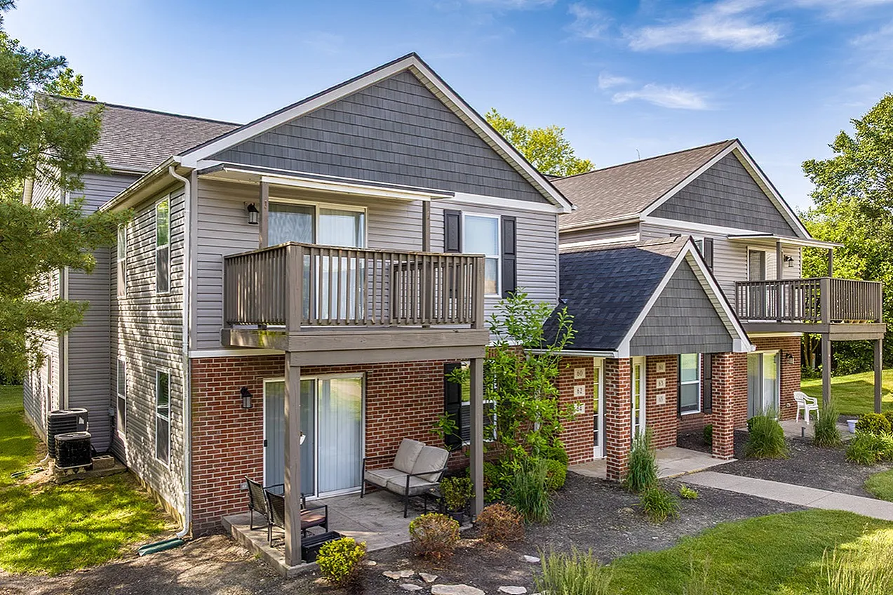 Charming two-story apartment building with inviting private balconies, surrounded by lush greenery and a tranquil setting.