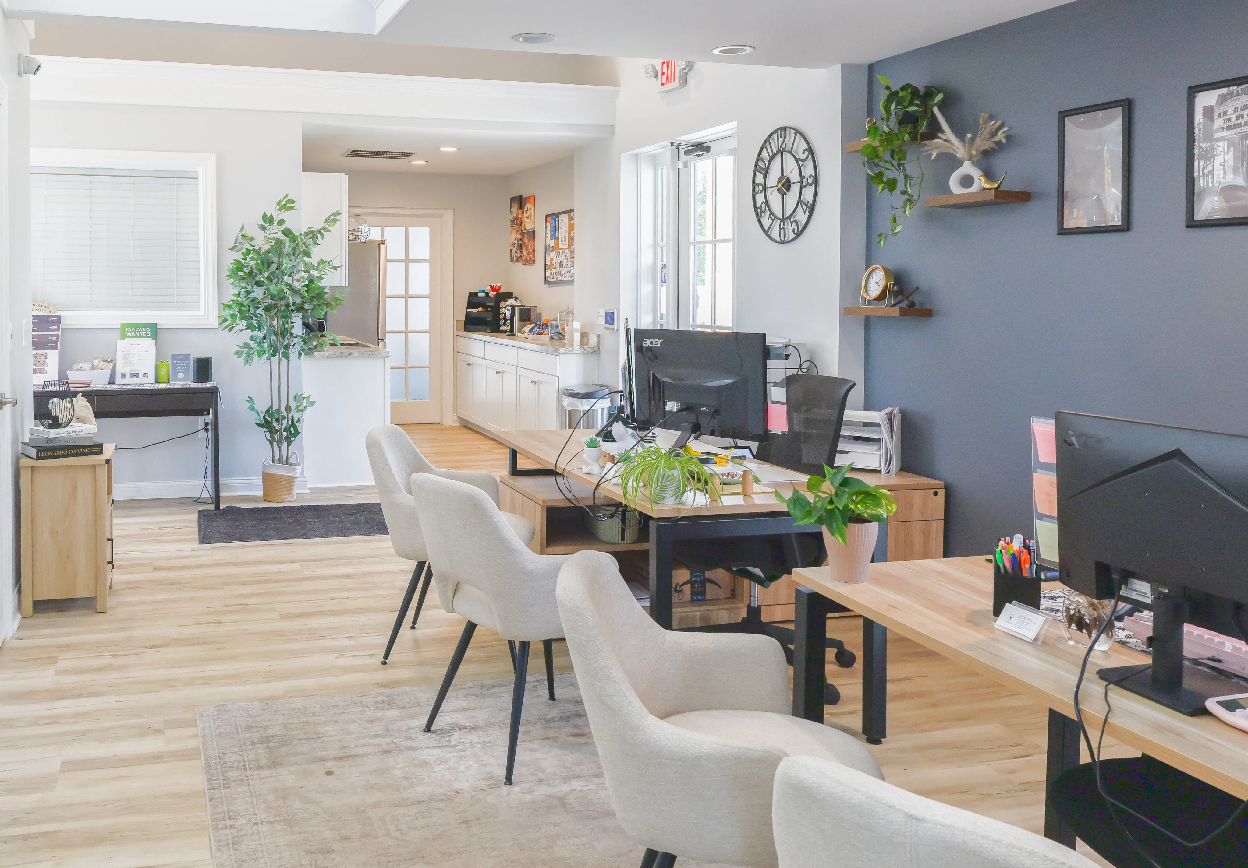 Modern open-concept office space featuring sleek desks, comfortable seating, vibrant greenery, and abundant natural light.