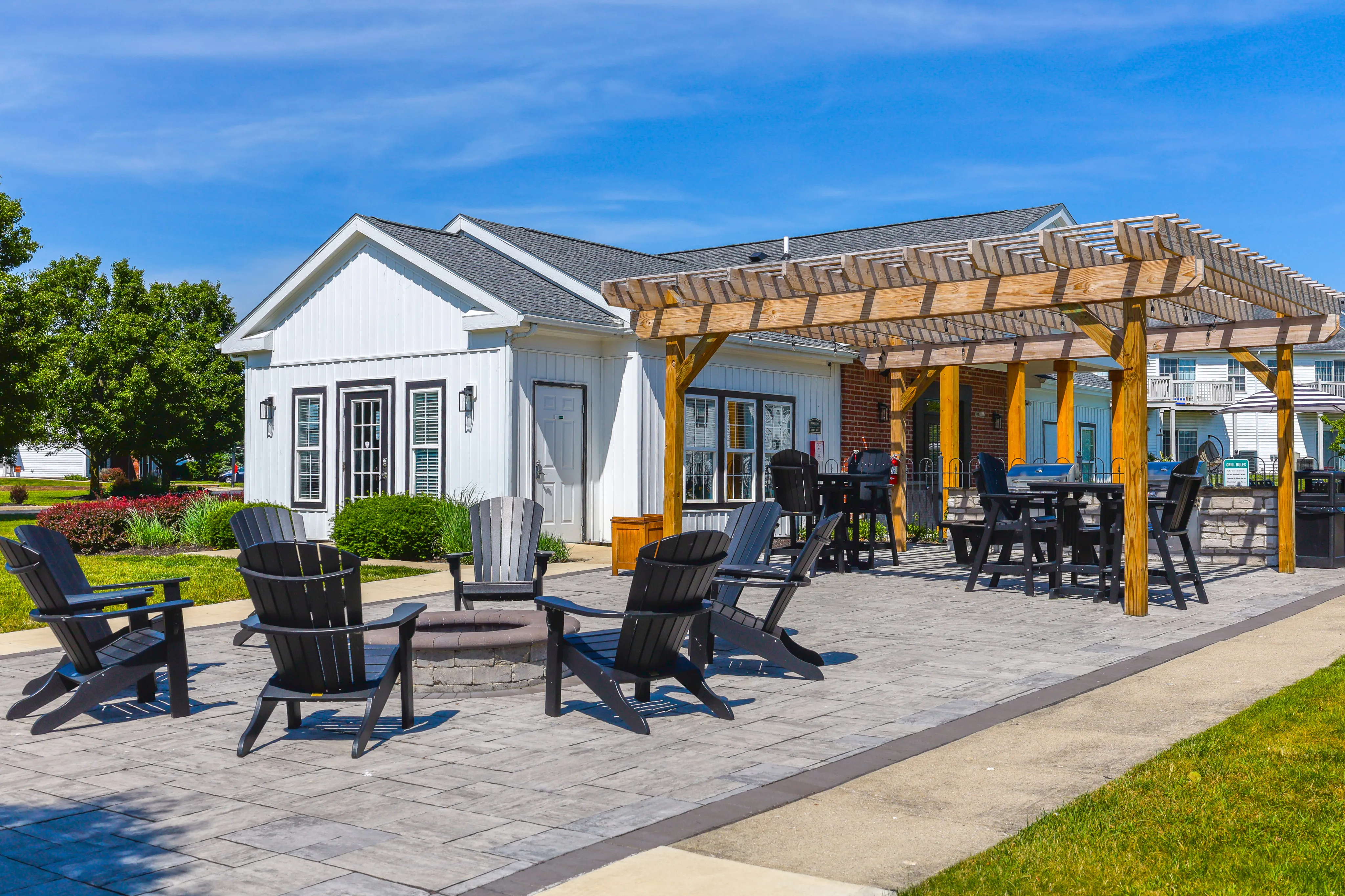 Charming outdoor patio area with cozy seating, a wooden pergola, and lush landscaping, perfect for relaxation and entertaining.