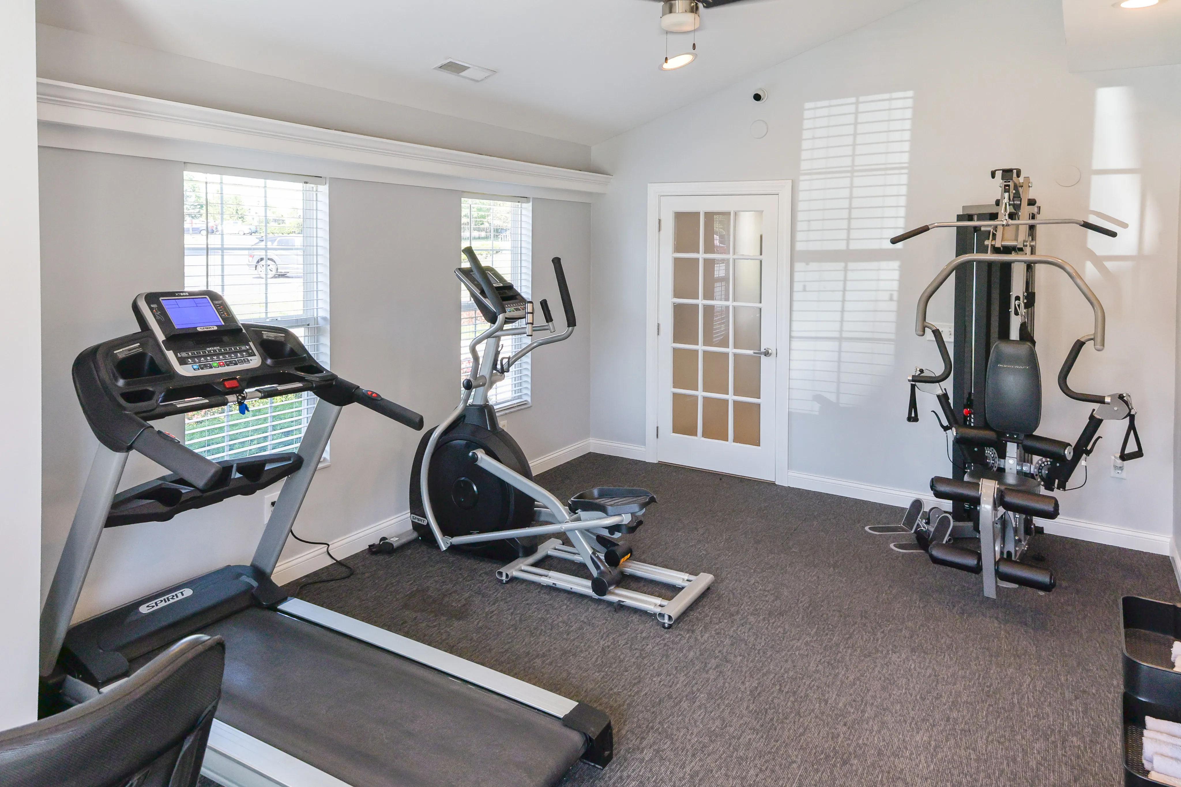 Bright and modern gym room equipped with a treadmill, stationary bike, and multi-station fitness machine.