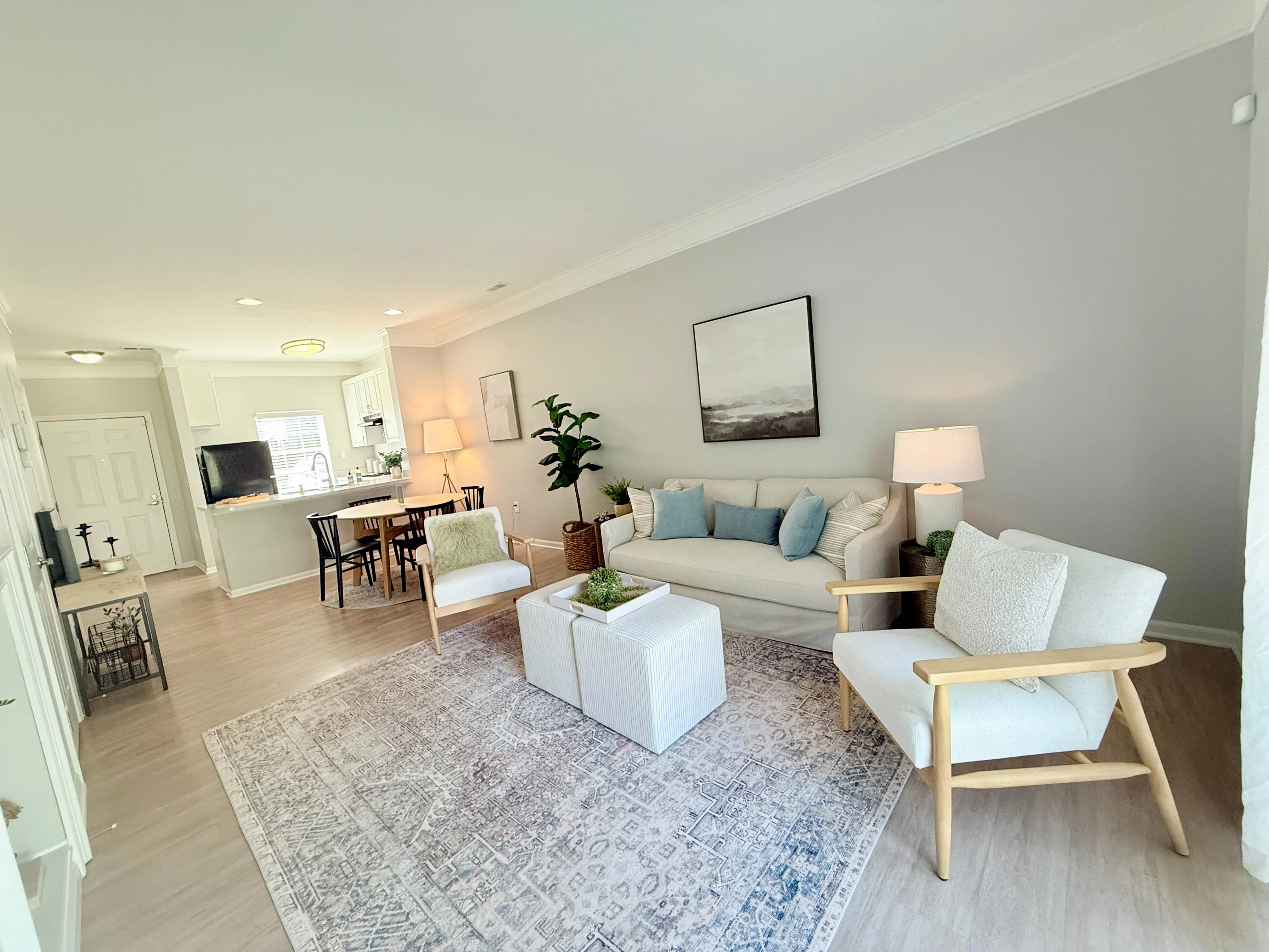 Bright and inviting living area with chic decor, cozy seating, and an open kitchen, perfect for modern living.