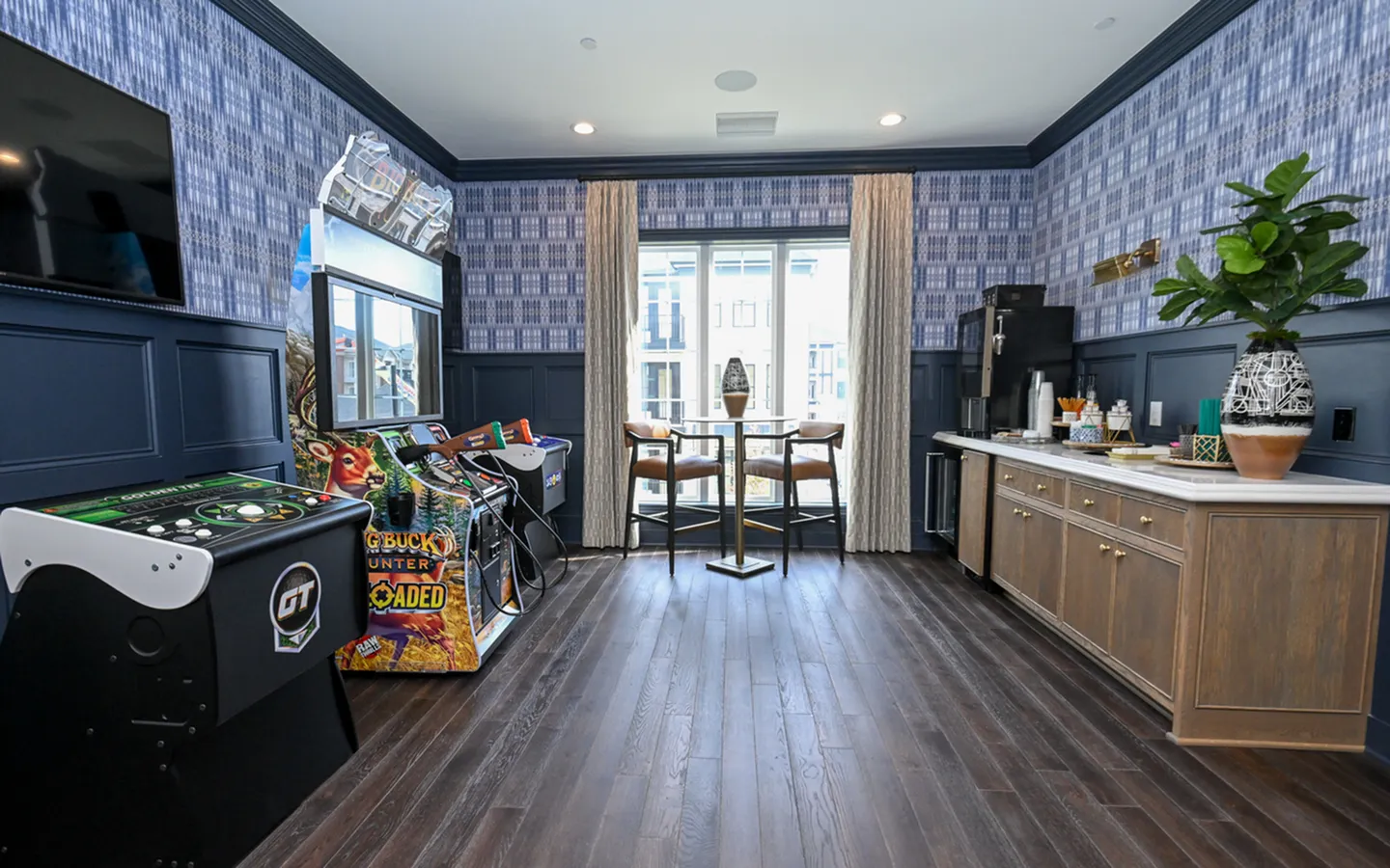 Chic entertainment room featuring arcade games, elegant seating, and a modern refreshment counter.