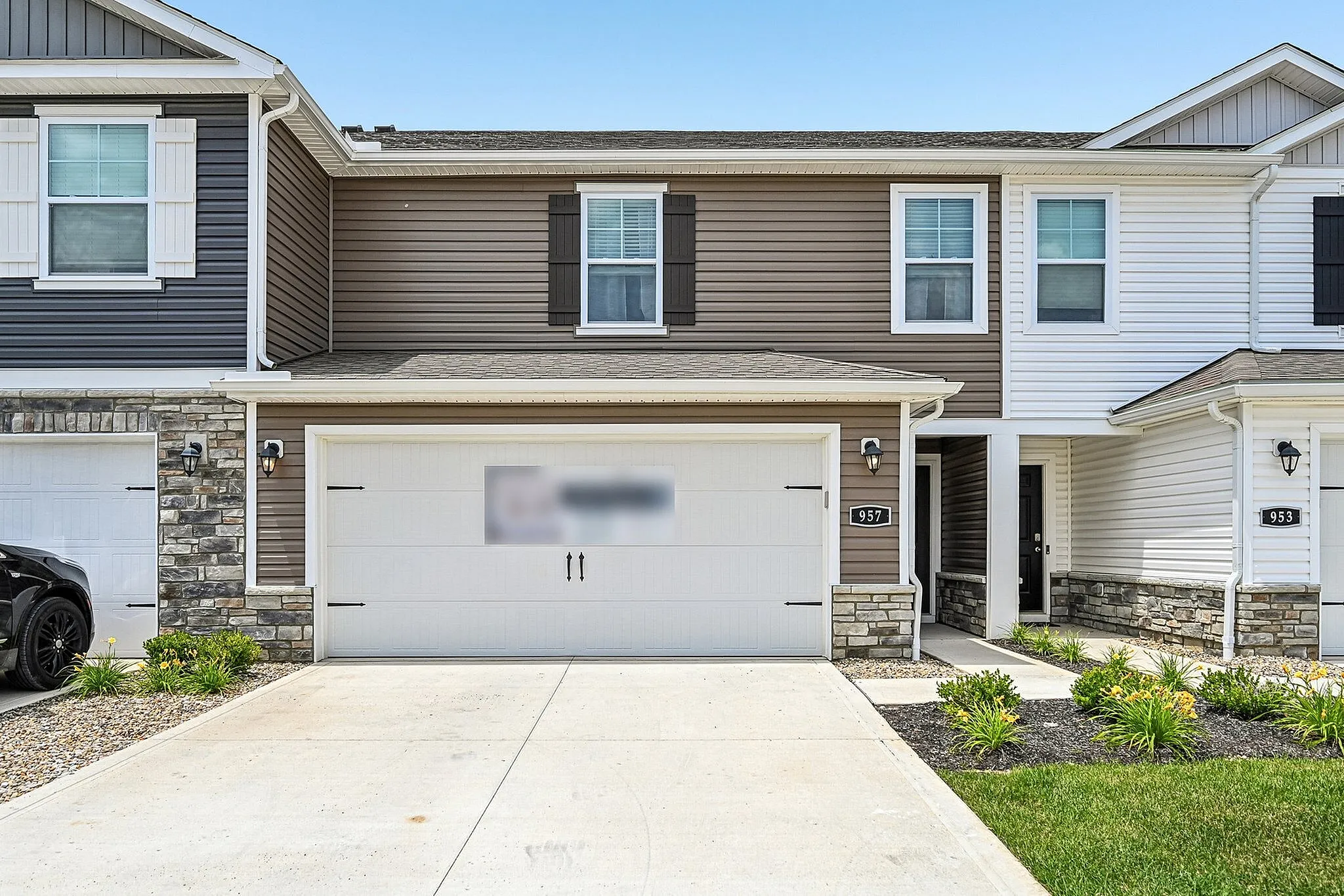 Charming townhouse with a modern facade, featuring a double garage and well-maintained front garden.