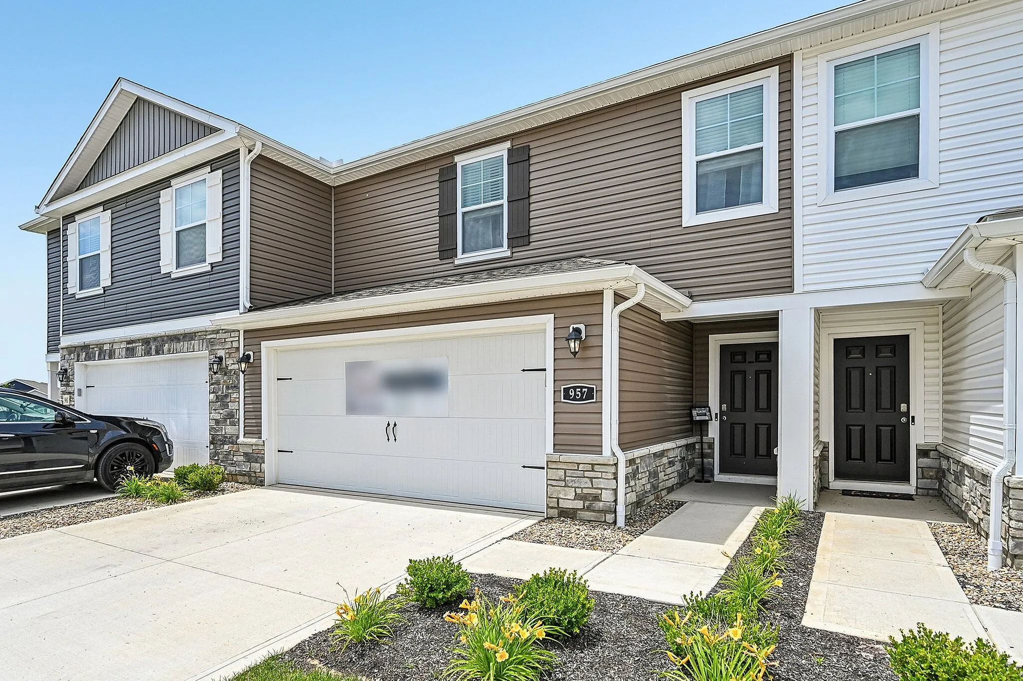 Charming townhouse with modern facade, featuring two stylish entrances and attached garage, set in a serene neighborhood.