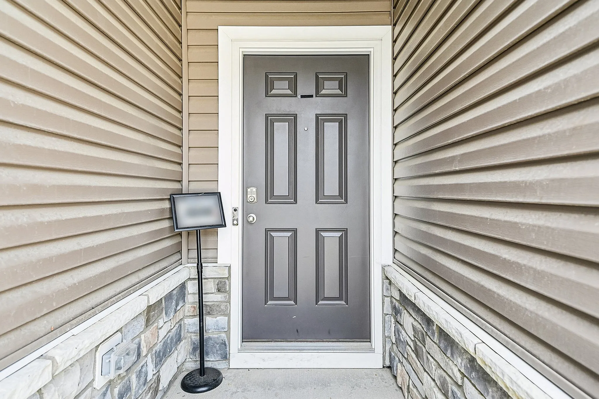 Inviting front entryway featuring a modern gray door with elegant paneling, framed by stylish siding and stone detailing.