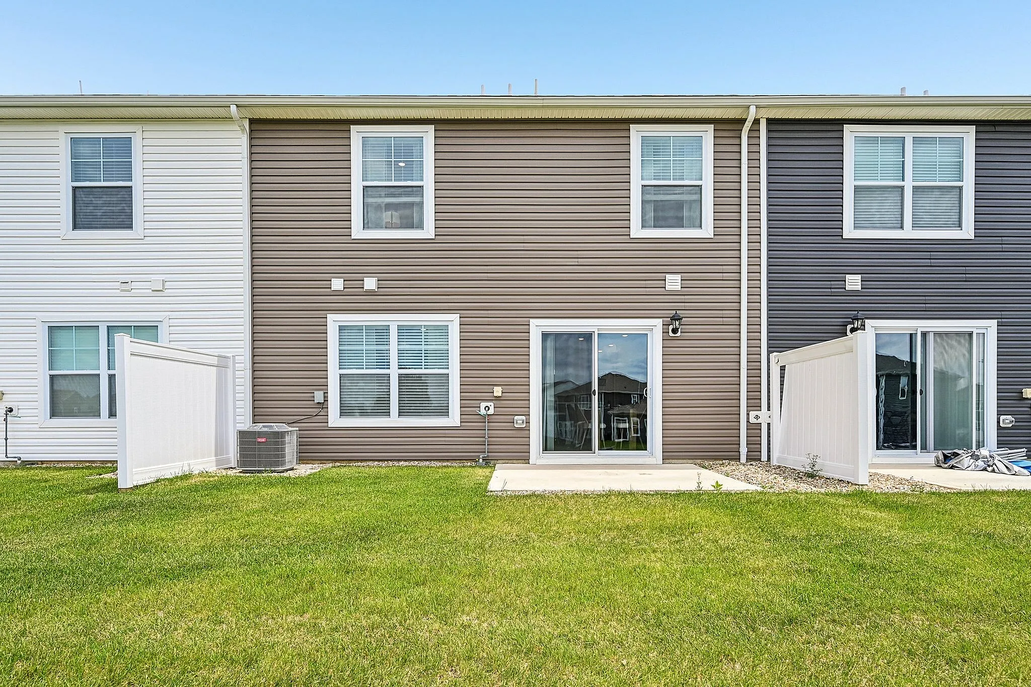 Charming townhouse exterior with clean lines, modern siding, and a lush green backyard perfect for relaxation.