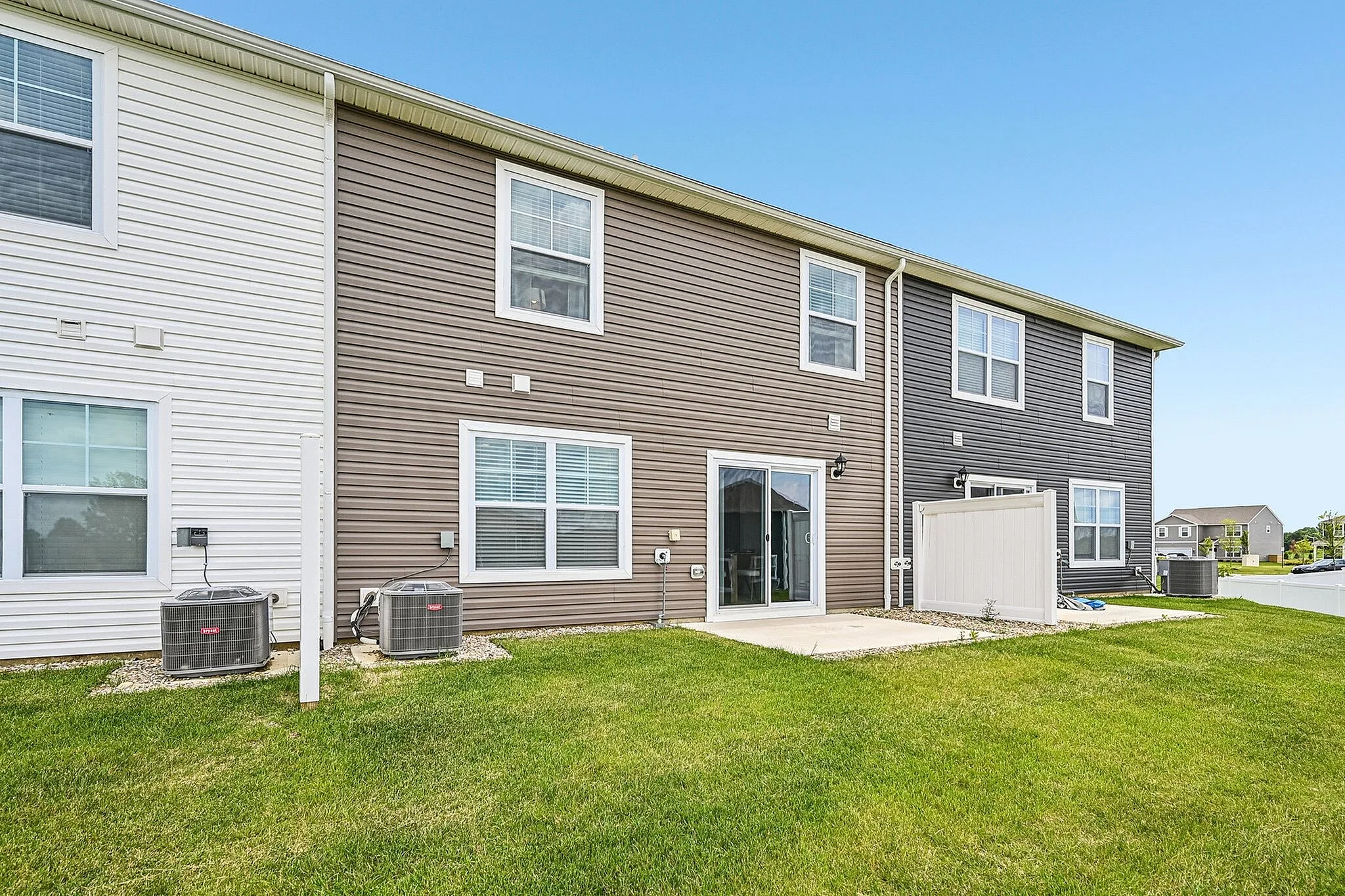 Charming townhouse exterior with modern siding, large sliding glass door, and manicured lawn, perfect for entertaining.