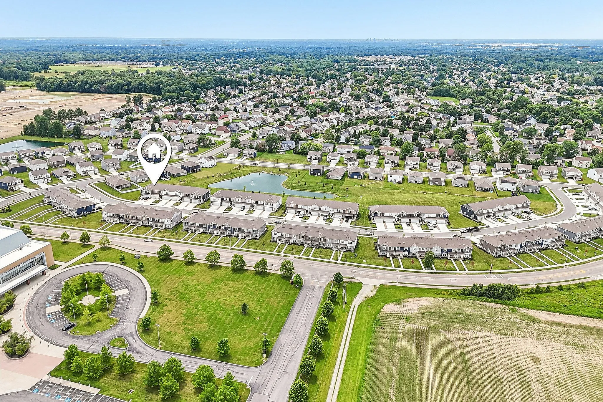 Aerial view of a charming suburban neighborhood with neatly arranged houses, lush greenery, and a central pond, showcasing an idyllic and peaceful community setting.