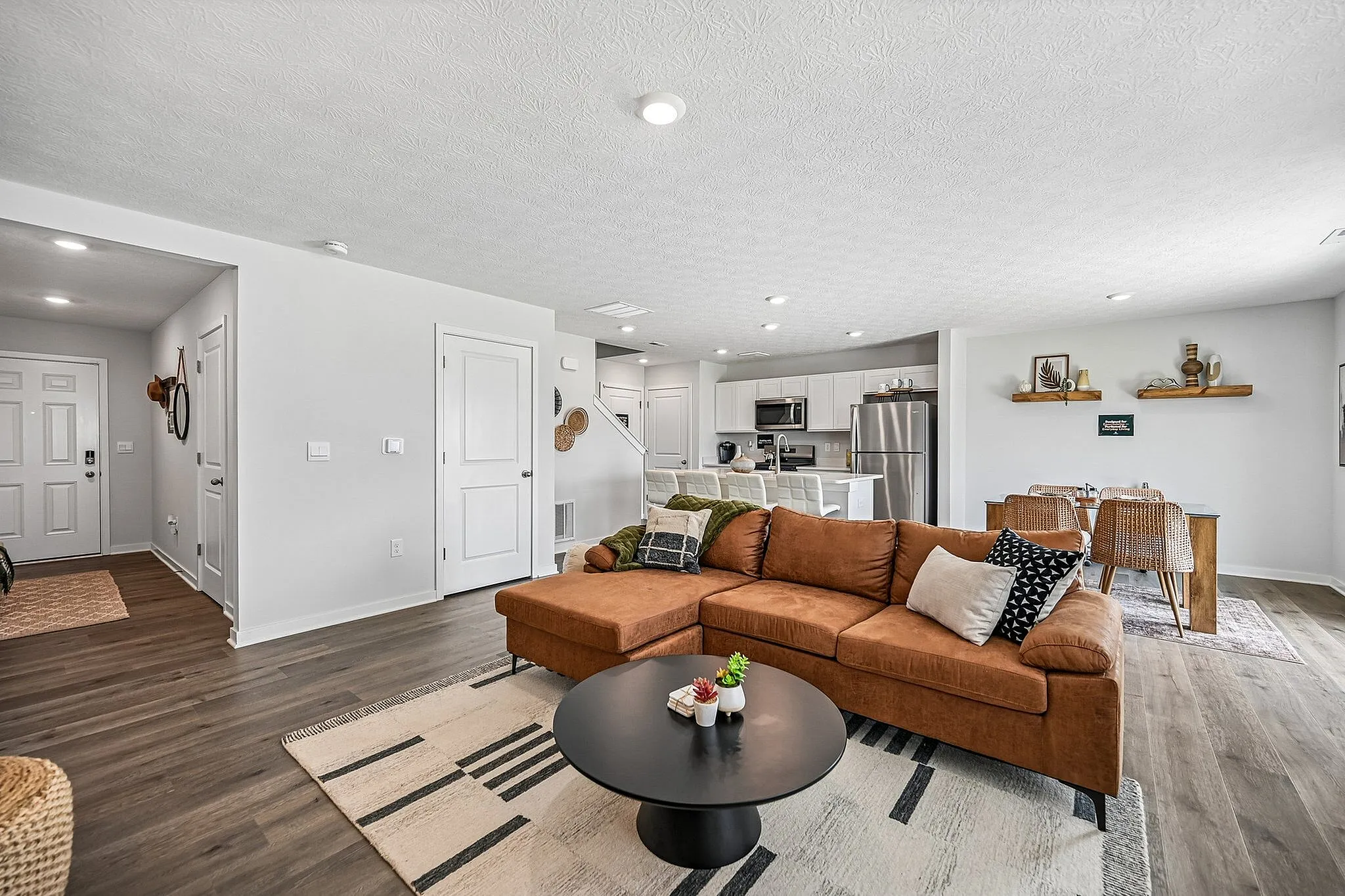 Inviting open-plan living space featuring a modern kitchen with sleek stainless steel appliances, a cozy brown sectional sofa, and a stylish dining area perfect for entertaining.
