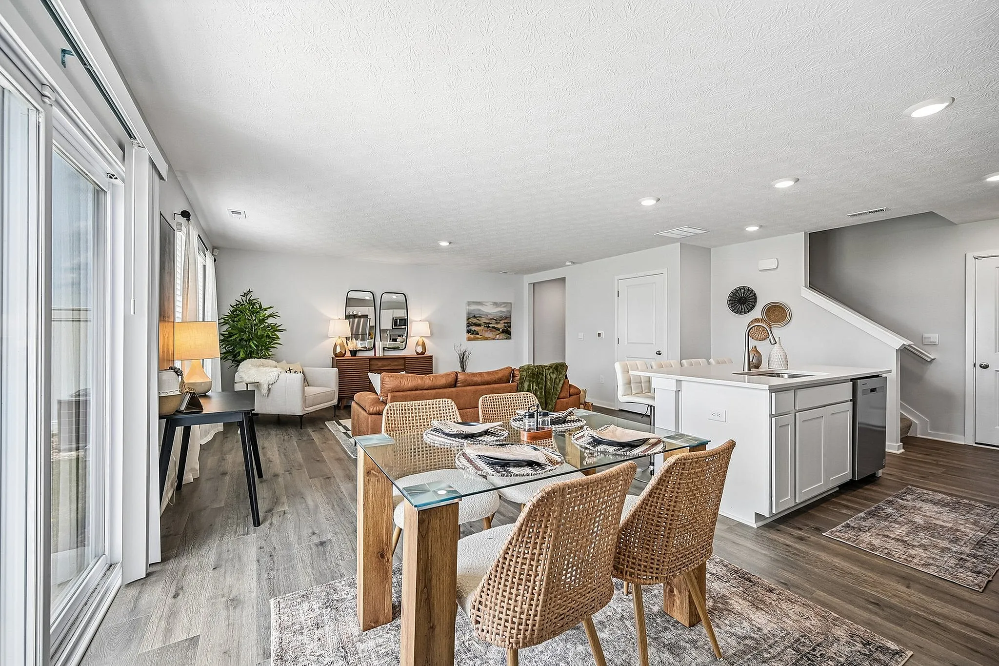 Modern open-concept living space featuring a stylish dining area, cozy seating with plush couches, and a sleek kitchen island, all highlighted by natural light and elegant decor.