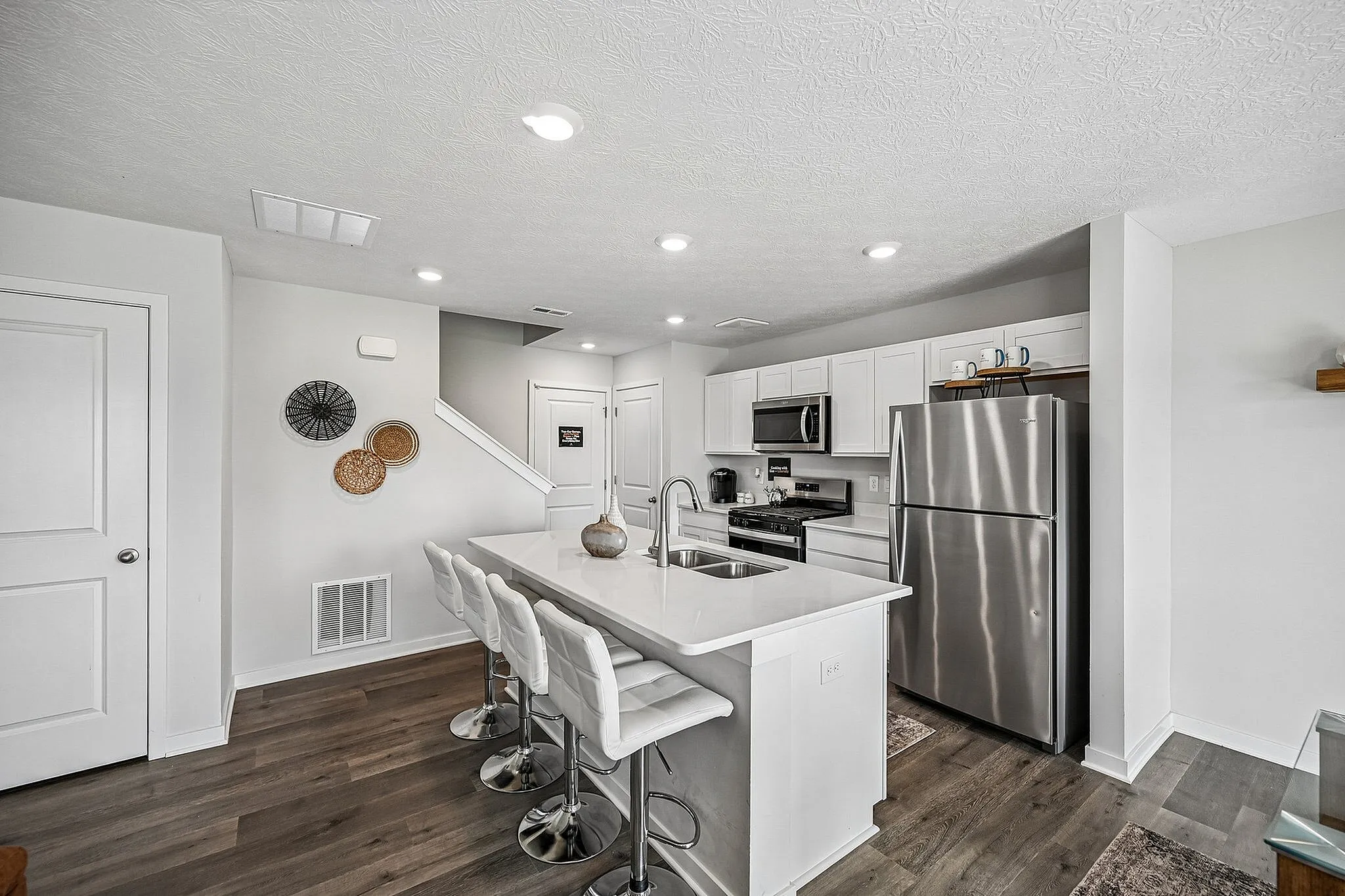 Modern kitchen showcasing sleek white cabinetry, stainless steel appliances, and an inviting breakfast bar with stylish stools.