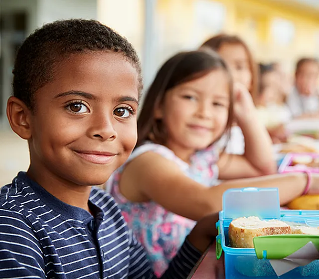 Joyful children enjoying lunch outdoors at a colorful table, fostering a sense of community and togetherness.