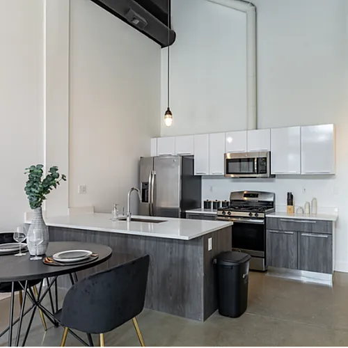 Modern kitchen with sleek appliances, stylish dining area, and elegant pendant lighting in a spacious open-plan apartment.