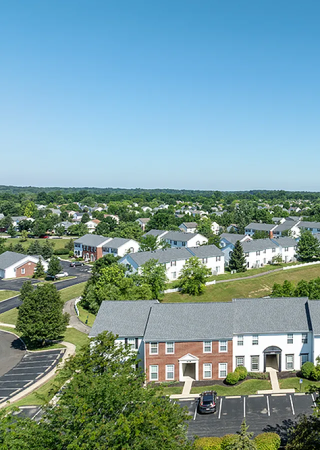 Charming suburban apartment complex with picturesque pond, lush greenery, and inviting neighborhood streets.