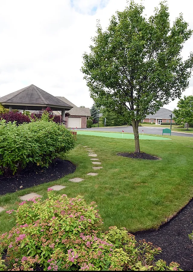 Charming garden view from an upscale neighborhood, featuring lush greenery, manicured lawns, and a quaint gazebo.