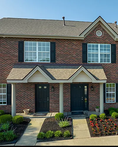 Charming brick townhouse with manicured landscaping and inviting entrance, perfect for comfortable living.