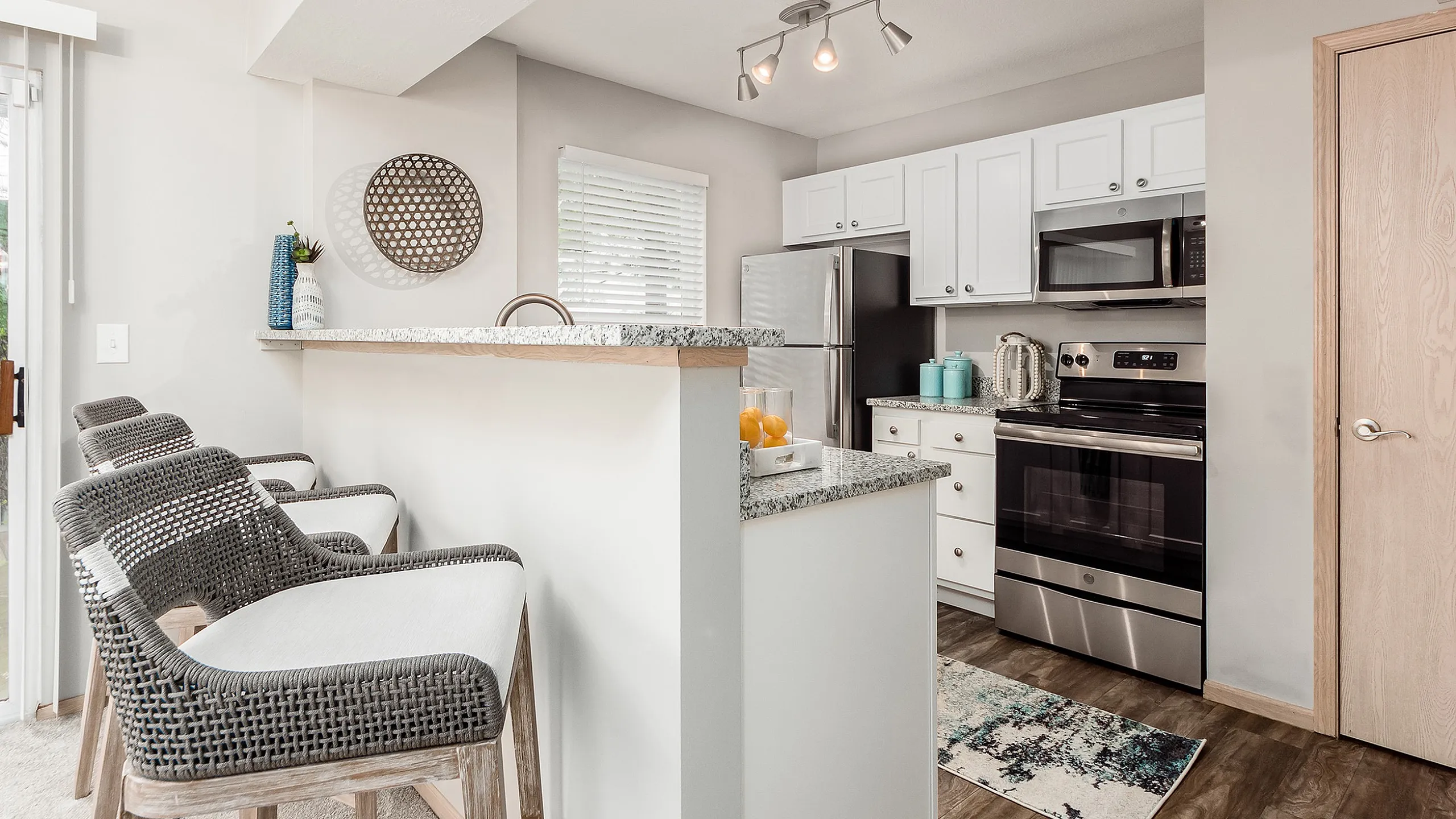 Modern kitchen with sleek granite countertops, stainless steel appliances, and elegant bar seating. Bright and inviting space with stylish decor accents.
