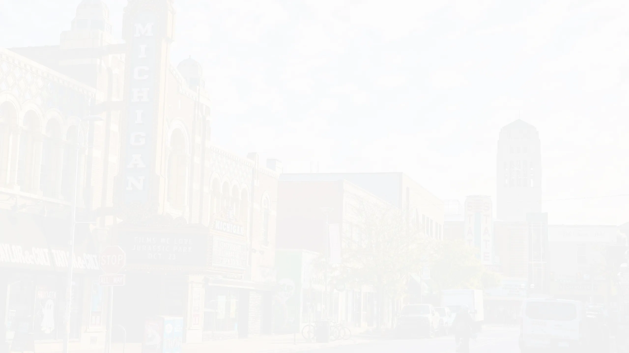 Quaint urban street view featuring historic buildings with charming architecture, including prominent theater signs on a sunny day.