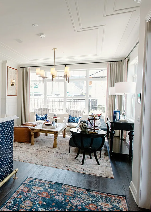 Elegant living room with modern lighting, blue-patterned decor, and large windows creating a bright, inviting space.