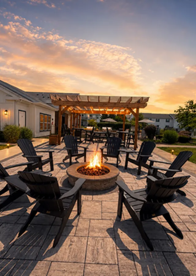 Elegant outdoor patio with a cozy fire pit surrounded by Adirondack chairs under a stunning sunset sky, creating a perfect gathering space.