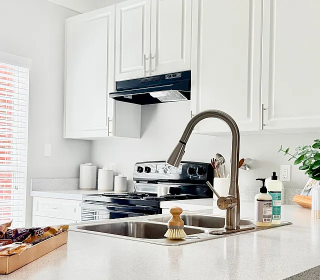 Modern kitchen with sleek white cabinets, a polished countertop, and stainless steel fixtures, offering plenty of natural light.