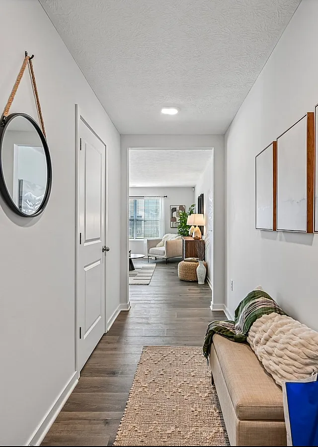 Inviting hallway leading to a bright, stylish living area with modern decor, cozy seating, and natural light.