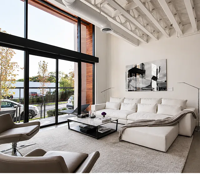 Modern living room with floor-to-ceiling windows, stylish white couch, and contemporary decor, offering abundant natural light and a serene view.