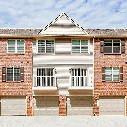Charming townhouse exterior with inviting balconies, stylish brick fa&ccedil;ade, and ample garage space.