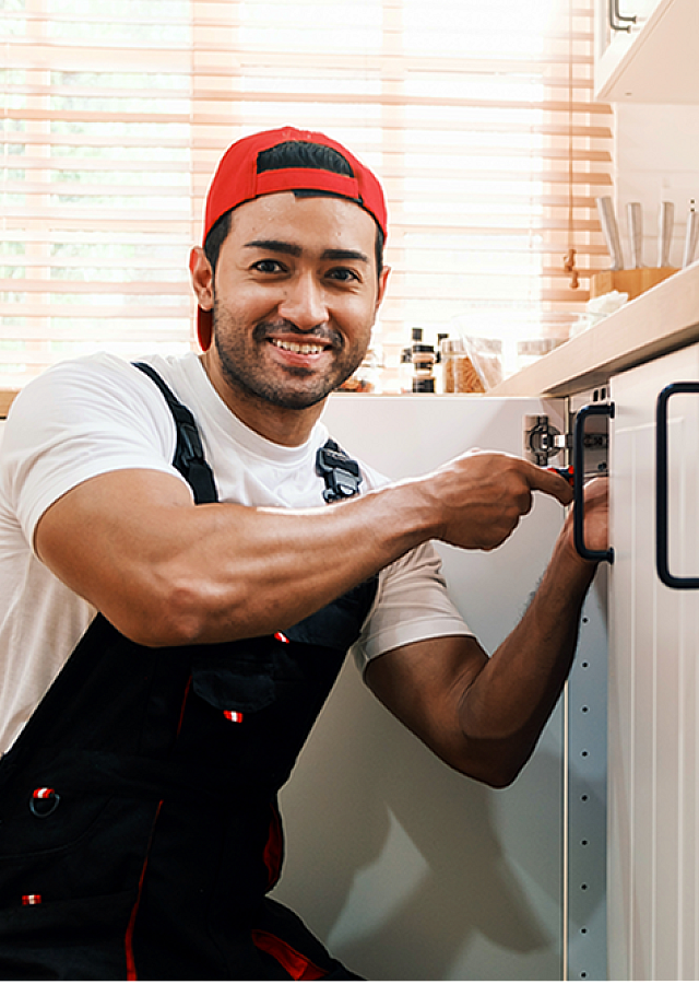 Cheerful handyman working on modern kitchen cabinetry, showcasing professional home maintenance services.