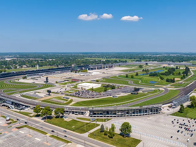 Expansive aerial view of the famous Indianapolis Motor Speedway racetrack surrounded by lush greenery, offering a thrilling and picturesque experience.