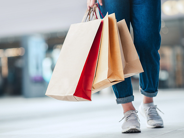 Chic shopping scene with a person holding vibrant, colorful shopping bags in a lively mall environment, showcasing an exciting shopping adventure.