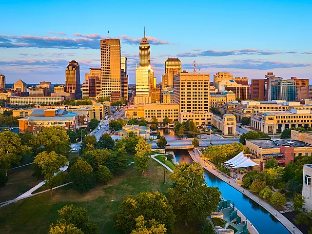 Vibrant cityscape of Indianapolis, IN showcasing a bustling downtown skyline with serene park setting and winding canal.
