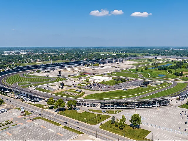 Spectacular aerial view of a renowned racing circuit, showcasing expansive green areas, winding tracks, and ample seating, perfect for adrenaline-pumping events.