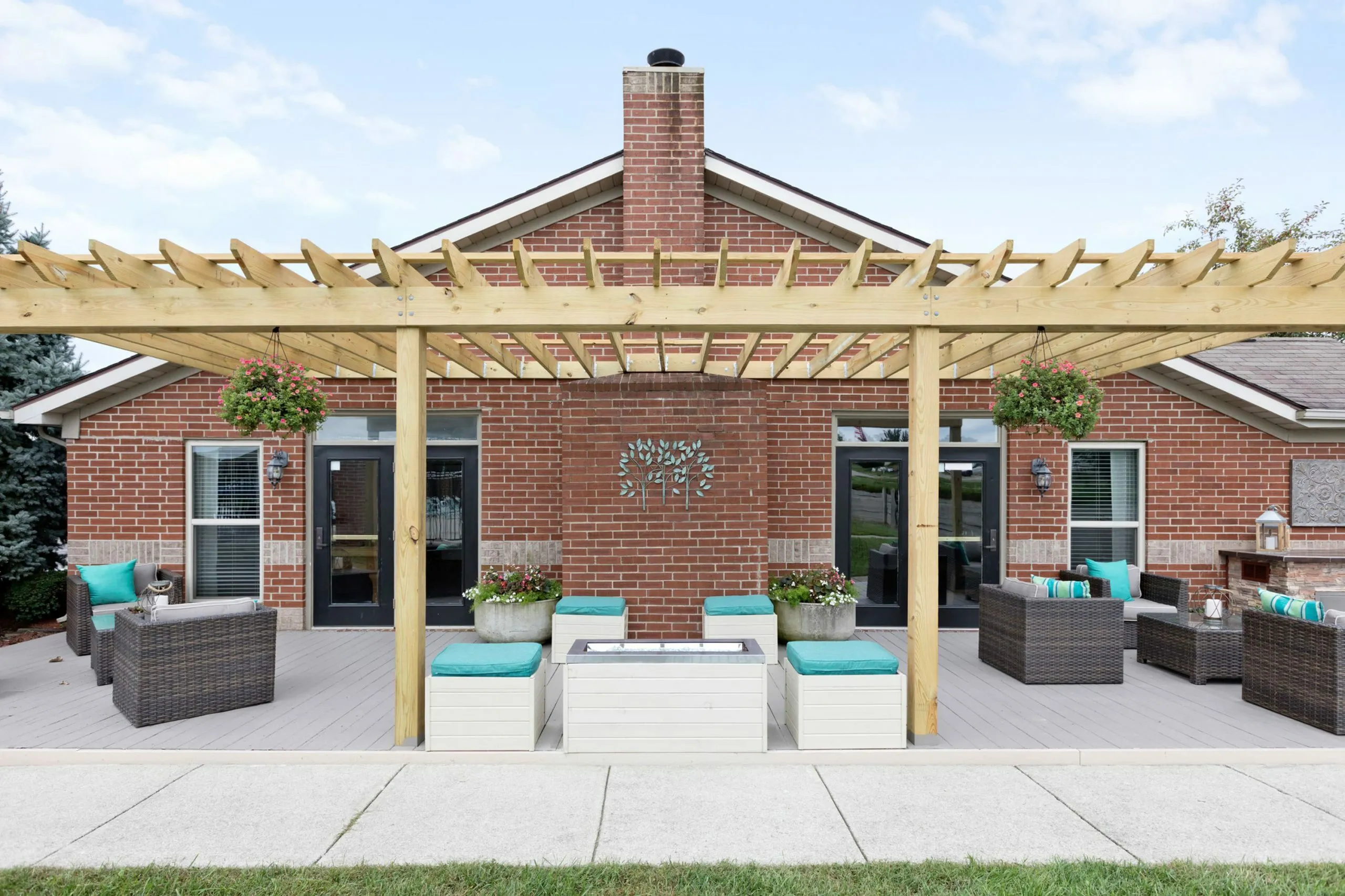 Charming patio with modern pergola, comfy wicker seating, and lush hanging plants against a stylish brick exterior.