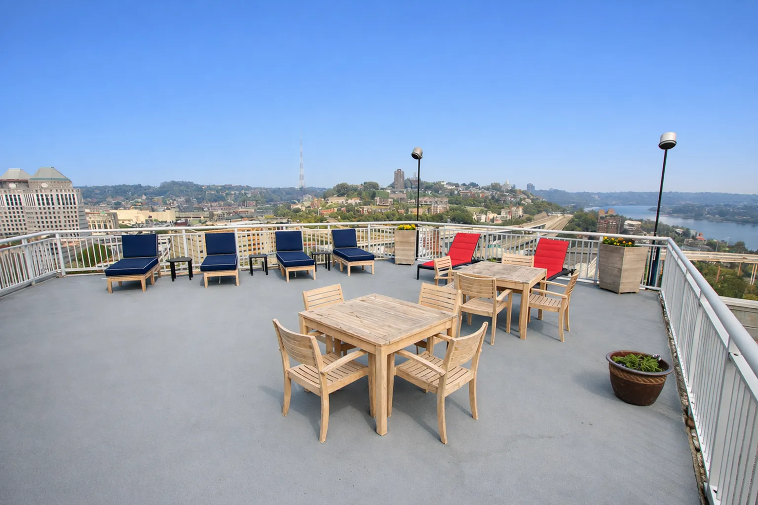 Stunning rooftop terrace with elegant seating, offering panoramic city and river views under a clear blue sky.