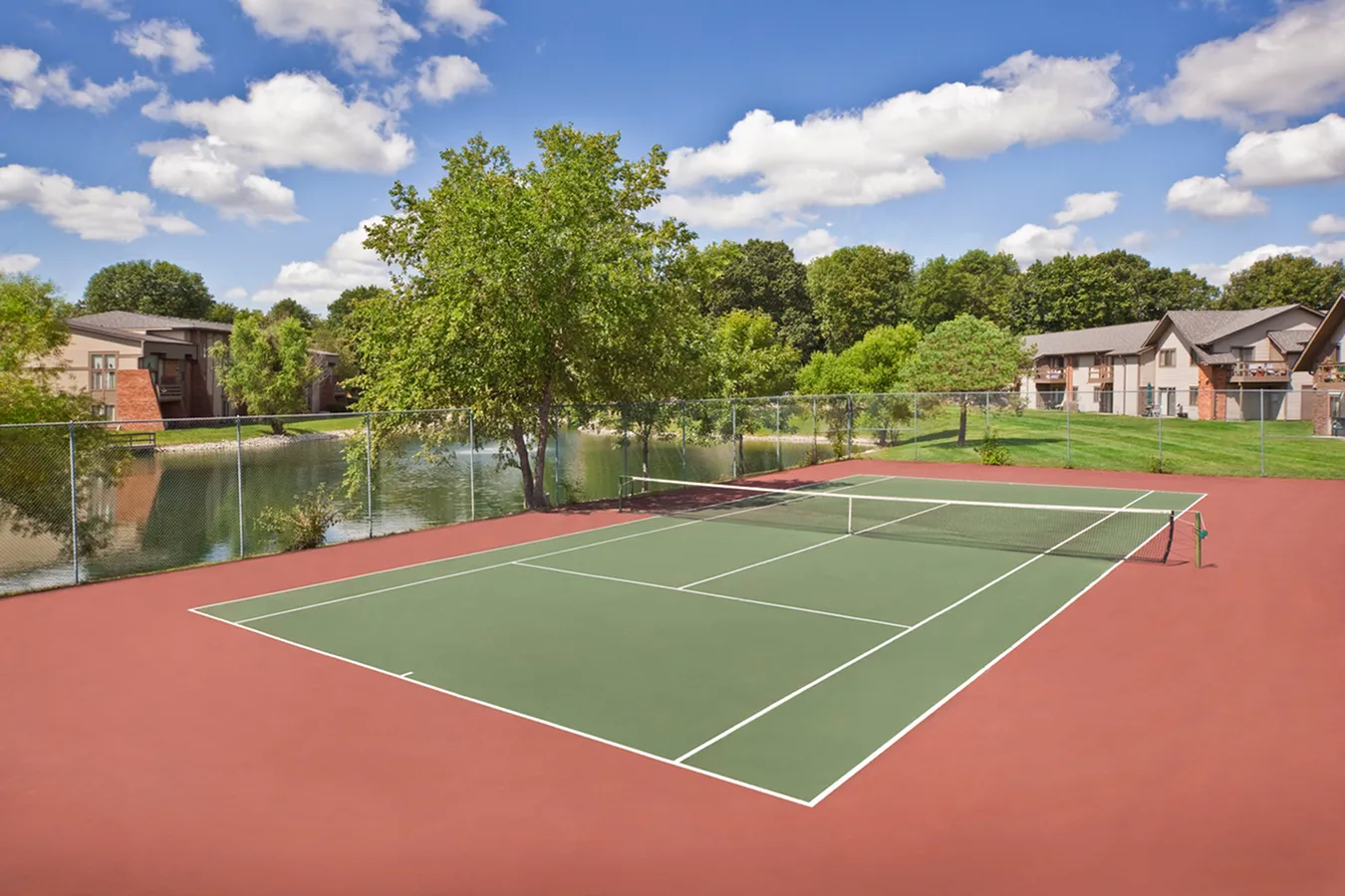 Landmark Apartments Beautiful tennis court surrounded by lush greenery and scenic water views, ideal for active living.