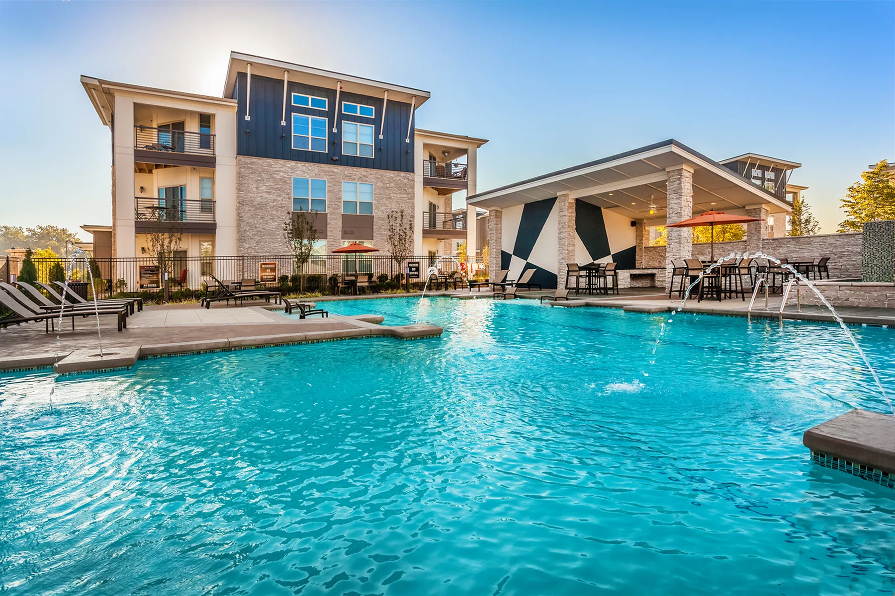 82 Flats featuring a sparkling pool with modern lounge chairs, stylish outdoor seating area, and contemporary architecture.