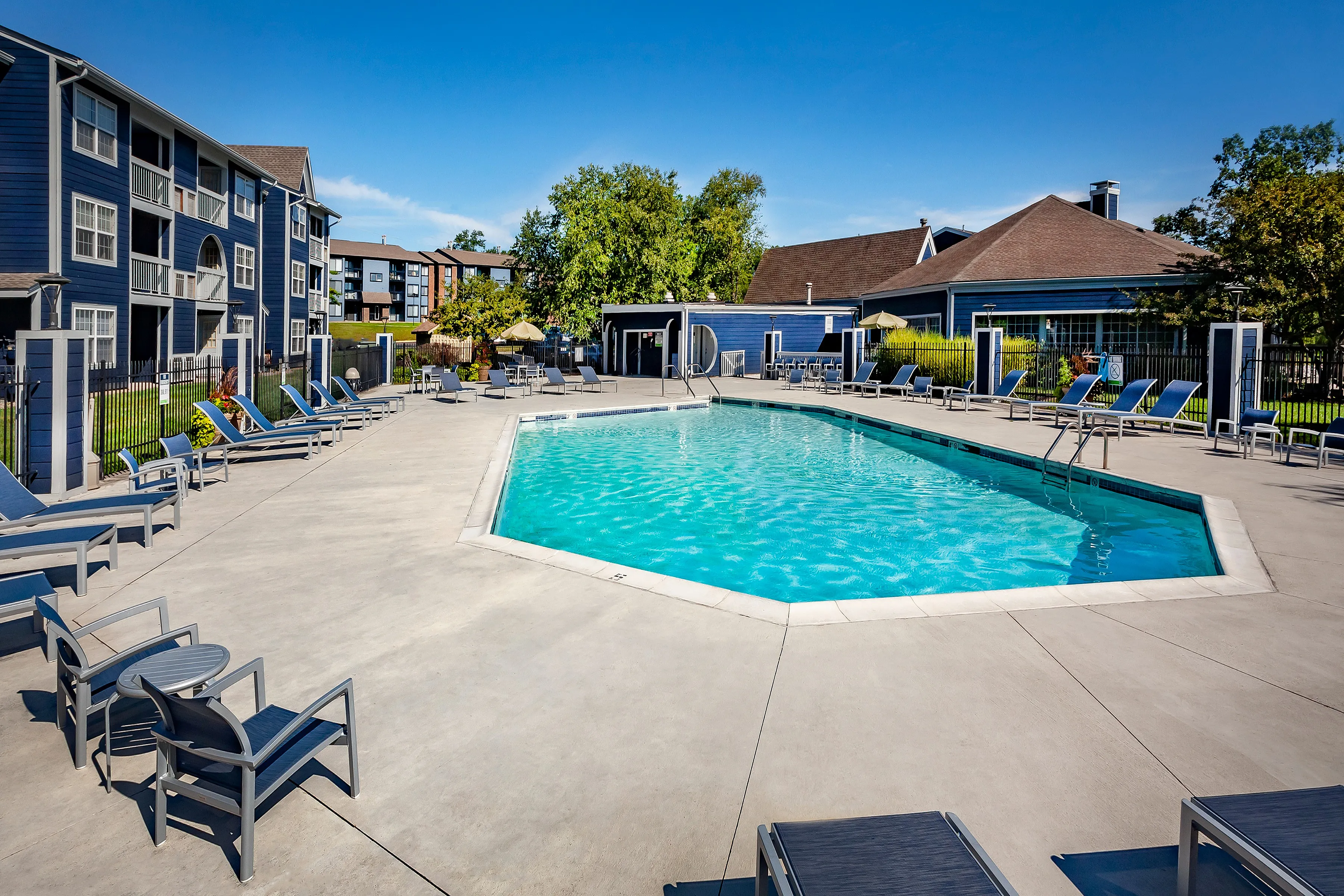 Inviting apartment community with a refreshing outdoor pool, surrounded by comfortable lounge chairs and lush greenery, perfect for relaxation and enjoyment.