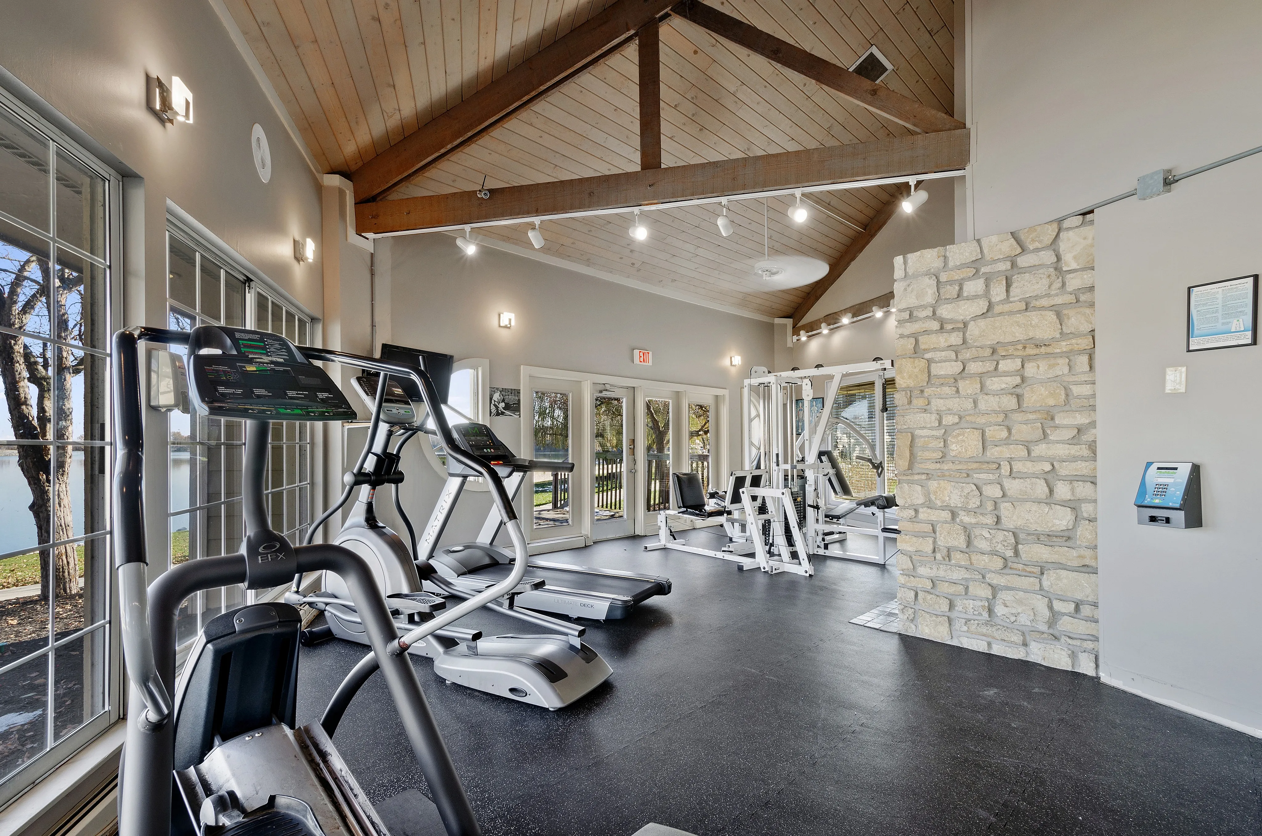 Modern fitness center with state-of-the-art exercise machines, high ceilings, and large windows providing scenic views.