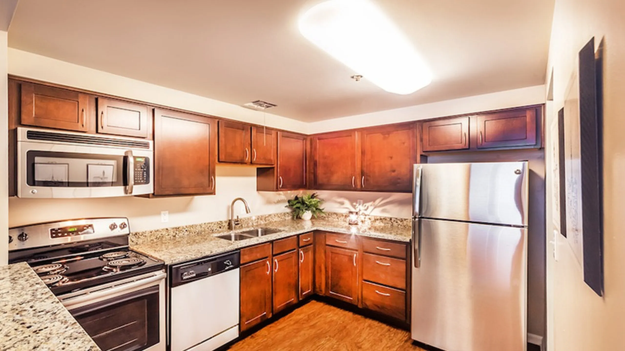 Modern kitchen with granite countertops, stainless steel appliances, and rich wooden cabinets, offering a warm and inviting cooking space.