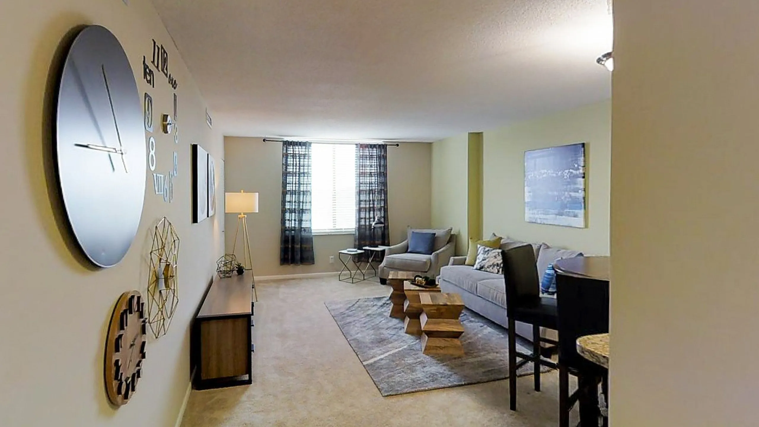 Modern living room with elegant decor, featuring a stylish sofa, contemporary wall art, unique geometric coffee tables, and large windows for natural light.