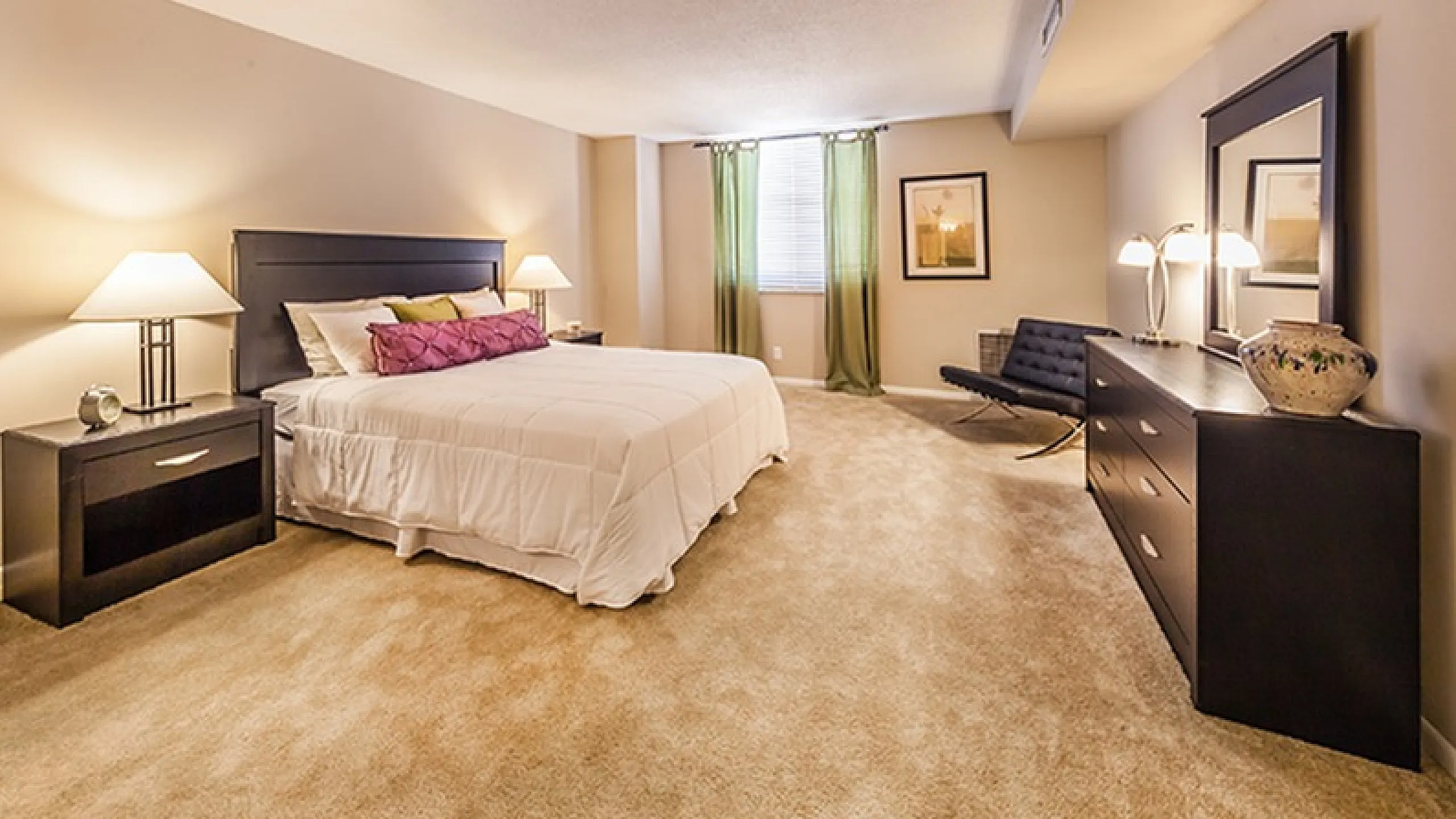 Elegant bedroom with a plush carpet, king-sized bed, modern lamps, and stylish decor creating a warm, inviting atmosphere.