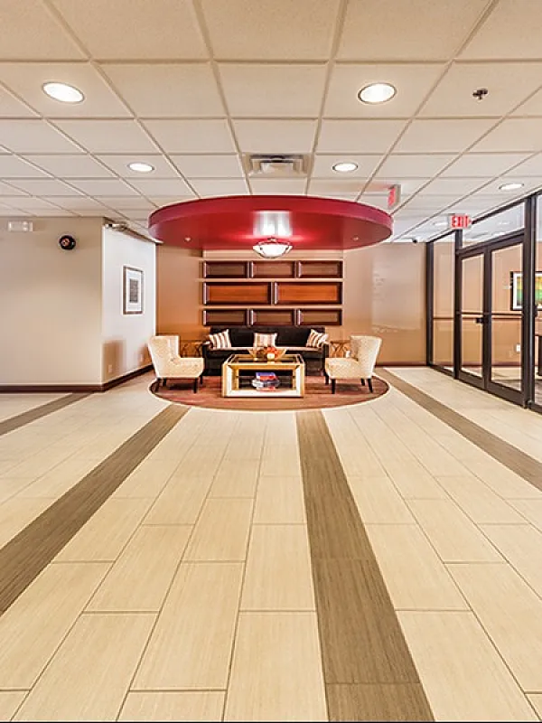 Luxurious apartment lobby with elegant lighting, comfortable seating area, and modern wooden accents.
