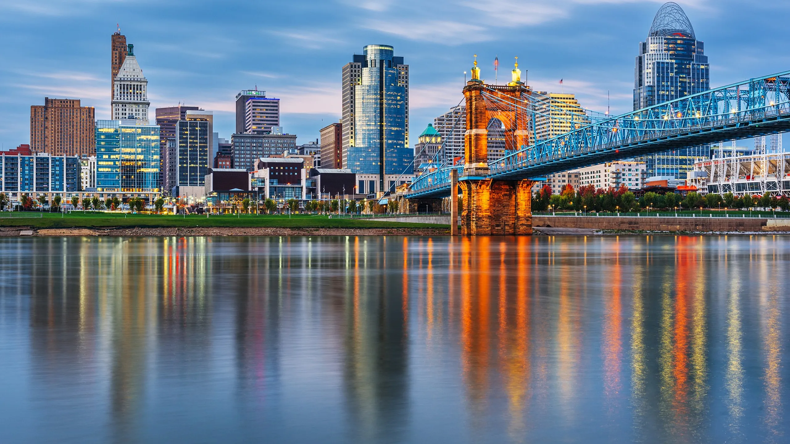 Captivating cityscape with a stunning suspension bridge and skyscrapers reflecting in a tranquil river.
