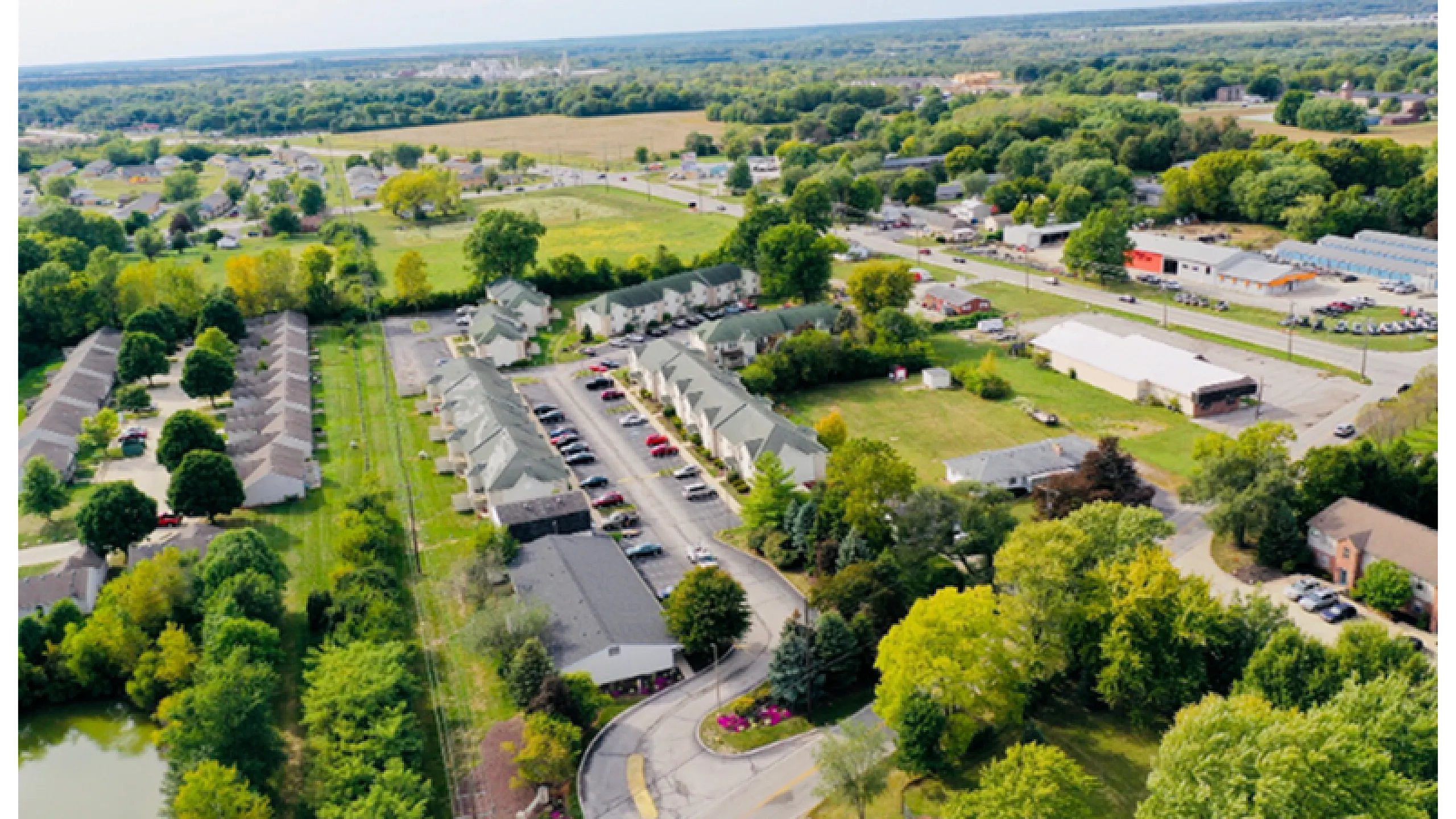 Charming aerial view of a serene residential community with lush greenery, ample parking, and a peaceful suburban setting.